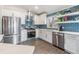 Modern kitchen with white cabinets, stainless steel appliances, and eye-catching blue tile backsplash at 1419 Trail Boss Ln, Brandon, FL 33511