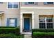 Inviting entryway with a blue front door framed by manicured hedges and a beige textured wall at 15733 Fishhawk Falls Dr, Lithia, FL 33547