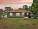 View of the backyard showcasing its screened lanai and spacious yard with sunset skies at 2016 Alameda Dr, Spring Hill, FL 34609