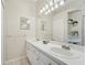 This bathroom features dual sinks, tiled floors, great lighting and a large mirror at 2016 Alameda Dr, Spring Hill, FL 34609