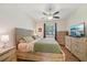 This cozy bedroom features wood floors, a ceiling fan, large dresser and flat screen television at 2016 Alameda Dr, Spring Hill, FL 34609