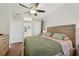 This cozy bedroom features wood floors, a ceiling fan, large dresser and a view of the en suite bathroom at 2016 Alameda Dr, Spring Hill, FL 34609