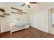 Bedroom/Bedroom with wood-look flooring, ceiling fan, wall shelves, and a crib near a closet at 2016 Alameda Dr, Spring Hill, FL 34609