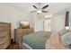 This cozy bedroom features wood floors, a ceiling fan, large dresser, flat screen television, and bathroom entrance at 2016 Alameda Dr, Spring Hill, FL 34609