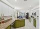 Bright kitchen featuring granite countertops, white appliances, and green cabinets; open to the living area at 2016 Alameda Dr, Spring Hill, FL 34609
