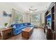 Bright living room with a plush blue sectional sofa, a wooden coffee table, and large windows with natural light at 2016 Alameda Dr, Spring Hill, FL 34609