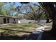 Spacious backyard features mature shade trees, concrete path, picnic table, and white privacy fence at 2105 Curry Rd, Lutz, FL 33549