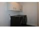 A sleek laundry room features modern black washer and dryer units and white cabinets at 2105 Curry Rd, Lutz, FL 33549