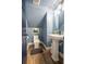 Half bath featuring modern vanity, sink, toilet, blue walls, and wood floors at 21867 Amelia Rose Way, Land O Lakes, FL 34637