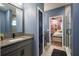 Bathroom boasts granite countertops, a gray cabinet, a doorway to the bedroom, and a tiled shower at 21867 Amelia Rose Way, Land O Lakes, FL 34637