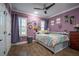 Bright bedroom features colorful decor, wood-look floors, and natural light from a window with shutters at 21867 Amelia Rose Way, Land O Lakes, FL 34637
