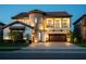 Elegant two-story home with a stone tower, balcony, tile roof, lush landscaping, and paver driveway at 21867 Amelia Rose Way, Land O Lakes, FL 34637