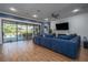 Cozy living room featuring wood-look tile floors, ample seating, and access to the screened-in pool at 21867 Amelia Rose Way, Land O Lakes, FL 34637
