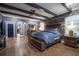This bedroom boasts a wood accent wall, wood beam ceiling, and wood-look tile flooring throughout at 21867 Amelia Rose Way, Land O Lakes, FL 34637