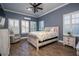 Comfortable main bedroom with wood flooring, natural light, plantation shutters, and decorative ceiling fan at 21867 Amelia Rose Way, Land O Lakes, FL 34637