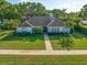 Charming single-story home with a lush green lawn, mature trees, and beautifully landscaped flowerbeds at 307 Oleander Rd, Belleair, FL 33756