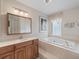 Well-lit bathroom with a soaking tub, wooden vanity, and a large mirror at 3171 Roxmere Dr, Palm Harbor, FL 34685