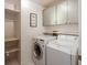 Well-lit laundry room featuring washer, dryer, storage shelves and white cabinets at 3171 Roxmere Dr, Palm Harbor, FL 34685
