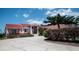 Charming single-story home features a red tile roof, lush landscaping, and a large driveway at 320 Bath Club Blvd S, North Redington Beach, FL 33708