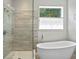 Modern bathroom with a glass-enclosed shower, freestanding tub, and a window for natural light at 3321 Mapleridge Dr, Lutz, FL 33558