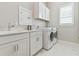 Bright laundry room features white cabinets, quartz countertop, stainless steel sink, and front load washer and dryer at 5858 Shorebird Br, Land O Lakes, FL 34638