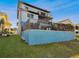 Home's backyard featuring a multi-story layout with a deck, stairs, and fenced yard with green grass at 6241 Bayside Dr, New Port Richey, FL 34652