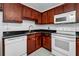 Kitchen featuring dark wood cabinets, white appliances, and black countertops at 7700 Sun Island S Dr # 404, South Pasadena, FL 33707