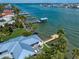 Aerial view of a waterfront home with a metal roof, a private dock, and lush landscaping on a sunny day at 785 Bay Esplanade, Clearwater Beach, FL 33767