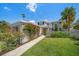 Charming two-story home with lush green lawn, mature landscaping and inviting walkway to the front door at 785 Bay Esplanade, Clearwater Beach, FL 33767