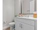 Clean and simple powder room features a white vanity, toilet, and decorative mirror at 923 Seagrape Dr, Ruskin, FL 33570