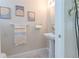 Cozy half-bathroom featuring a pedestal sink, decorative wall art, and neutral color palette at 9807 Carlsdale Dr, Riverview, FL 33578