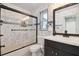 Updated bathroom featuring tiled walls, a sleek vanity, and a modern tub/shower combo with glass enclosure at 11467 93Rd St, Largo, FL 33773