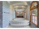 Elegant bathroom featuring a large soaking tub, arched window, and framed mirror reflecting the dual vanity at 1203 Parrilla De Avila, Tampa, FL 33613