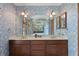 Bathroom with blue wallpaper, double vanity with framed mirrors and sconces, offering an elegant and functional space at 1203 Parrilla De Avila, Tampa, FL 33613