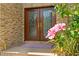 Elegant double front doors framed by vibrant flowers and brick facade create a welcoming entrance at 1203 Parrilla De Avila, Tampa, FL 33613