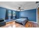 Blue bedroom features a ceiling fan, wood flooring and natural light from the windows at 12808 Candlewood Way, Hudson, FL 34667