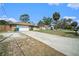 Long concrete driveway leading to a single-story home with stone accents and a detached garage at 1371 Meredith Dr, Spring Hill, FL 34608