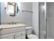 Well-lit bathroom featuring a glass door shower, and a vanity with a round mirror at 14053 Notreville Way, Tampa, FL 33624
