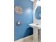 Stylish powder room featuring a pedestal sink, blue accent wall and decorative mirrors at 14053 Notreville Way, Tampa, FL 33624