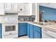 Functional kitchen area with blue cabinets, white appliances, and modern stainless steel features at 14053 Notreville Way, Tampa, FL 33624
