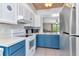 Efficient kitchen featuring blue cabinets, tiled backsplash, and stainless steel refrigerator at 14053 Notreville Way, Tampa, FL 33624