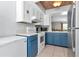 Bright kitchen with blue cabinets, white appliances, and a view into the living room at 14053 Notreville Way, Tampa, FL 33624