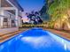 Evening shot of a sparkling pool and spa featuring ambient lighting, surrounded by lush landscaping for a serene atmosphere at 150 Chippewa Ave, Tampa, FL 33606