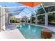 The home's screened-in pool features a spa, lounge chairs, and bright orange umbrella at 15702 Richboro Ct, Tampa, FL 33647