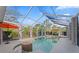 Screened-in pool with hot tub, sun umbrella, outdoor seating, and blue sky views at 15702 Richboro Ct, Tampa, FL 33647