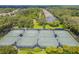 Overhead view of well-maintained outdoor tennis courts, surrounded by trees, shrubbery and fencing at 15861 Starling Water Dr, Lithia, FL 33547