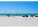 Beautiful wide sandy beach with clear blue ocean and multiple beachgoers at 18400 Gulf Blvd # 1211, Indian Shores, FL 33785