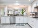 Modern kitchen featuring white cabinetry, stainless steel appliances, and marble countertops overlooking the living room at 18400 Gulf Blvd # 1211, Indian Shores, FL 33785