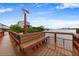 Waterfront deck with a wooden bench and railing overlooking the water and neighboring property at 19823 Gulf Blvd # 42, Indian Shores, FL 33785