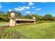 Community sign for East Lake Woodlands surrounded by lush landscaping on a beautiful day at 20 Iris Pl, Oldsmar, FL 34677